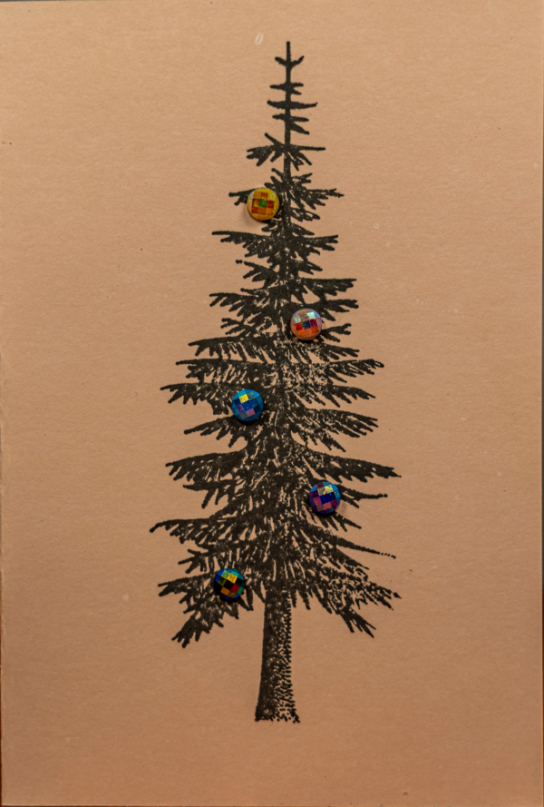 Handmade craft greeting card featuring a black evergreen tree with colorful reflective ornaments by Pickle Paper.
