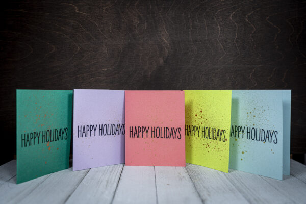 Set of five handmade “Happy Holidays” cards in assorted pastel and festive colors with metallic splatter accents by Pickle Paper.